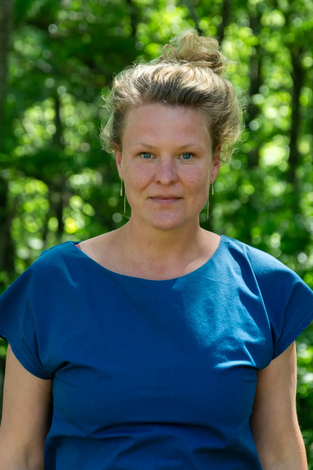 Portrait of Isabelle Zahradnyik outdoors, with sunlit woodland behind her
