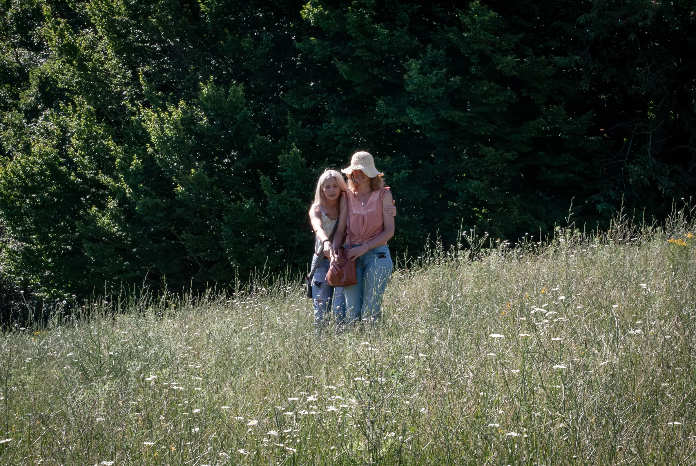 Two women embracing in a sunlit Tuscan meadow at the retreat