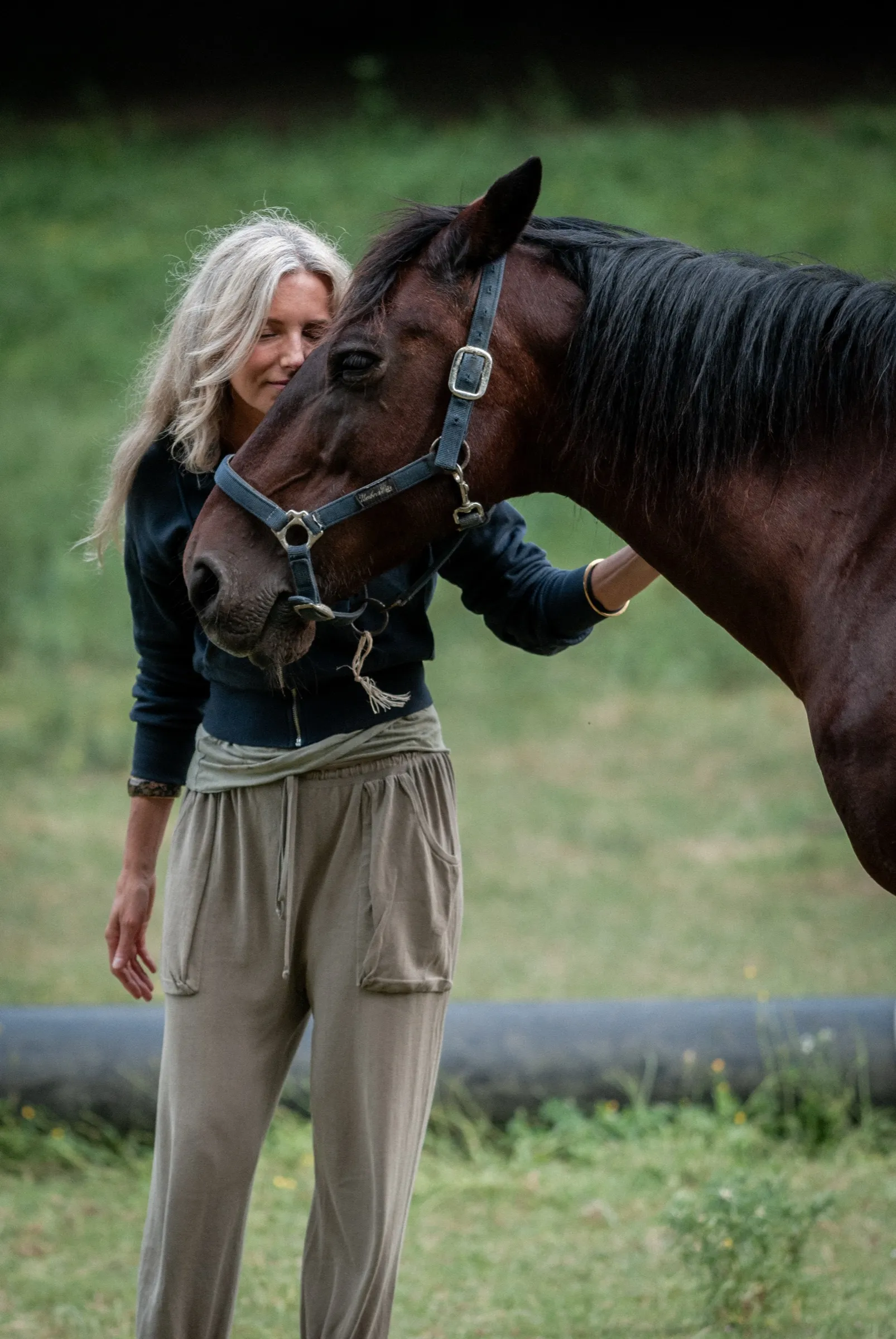 A woman resting her forehead gently against a horse